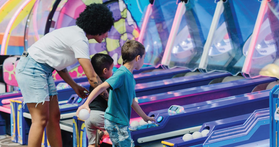 arcade-3-opt Women and 2 kids playing skeet ball in arcade